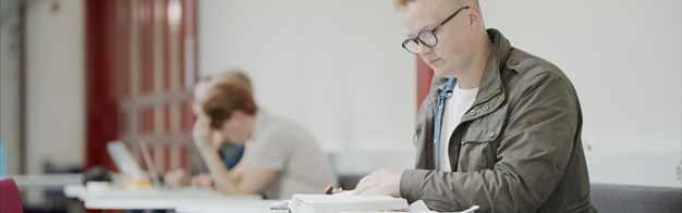 Albert sitter och läser en bok i skolmiljö