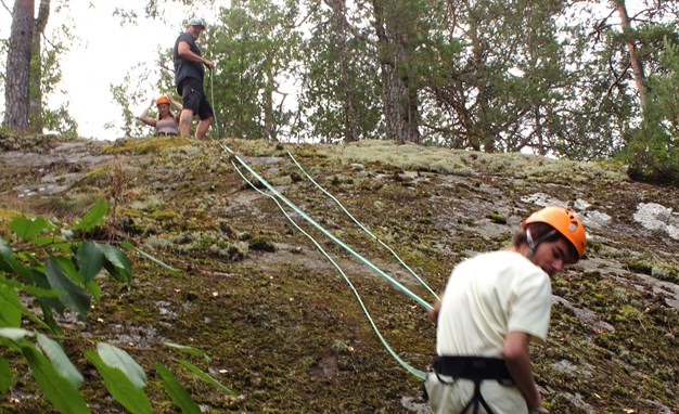 Jonathan som klättrar nedför en berg med hjälp på sig och en som hjälper honom med hans säkerhetslina.
